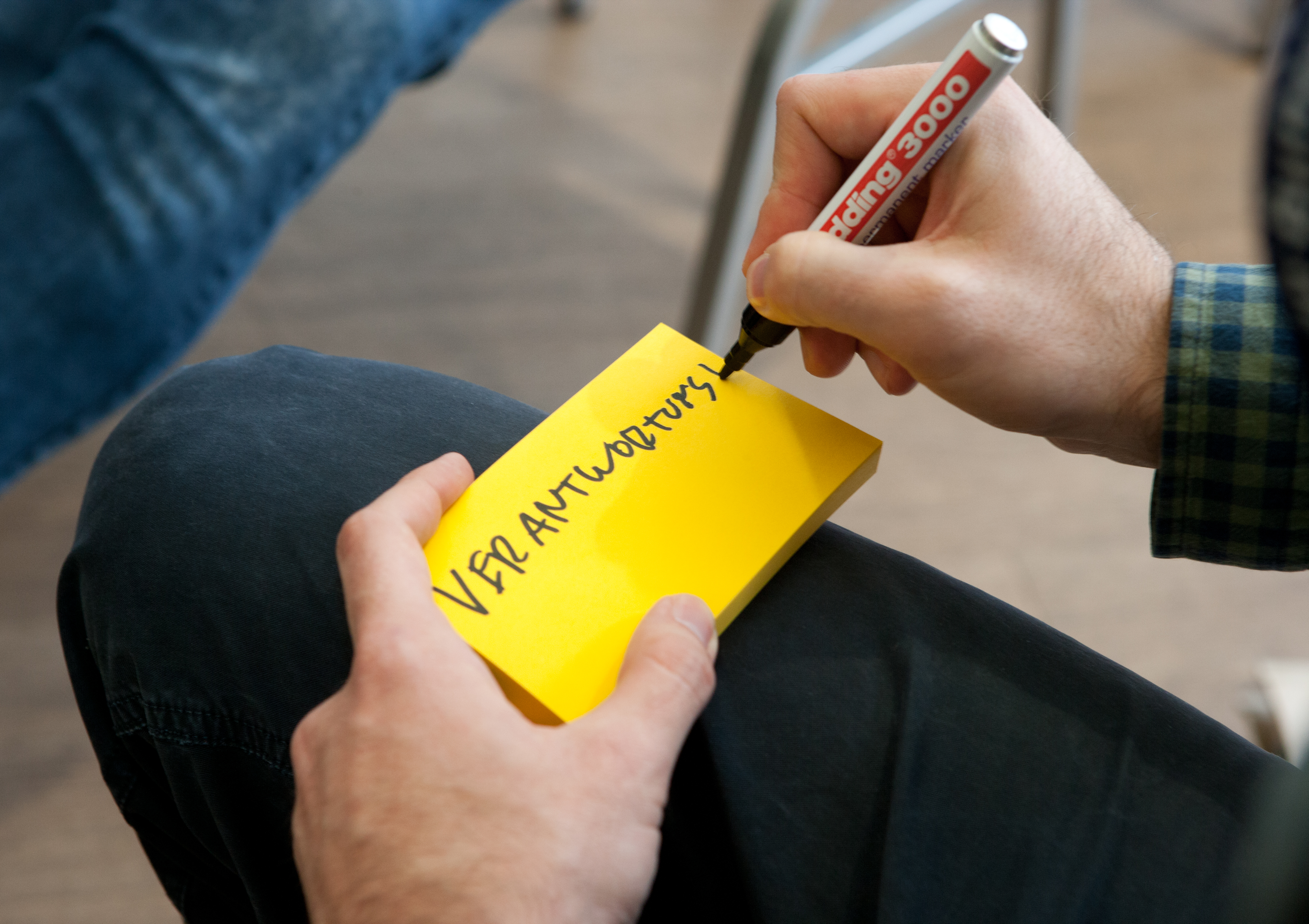 Nahaufnahme: jemand schreibt auf einen Post-it "Verantwortung"